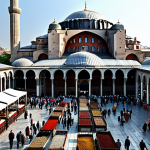 **

"A bustling scene in Istanbul, Turkey. The Hagia Sophia stands majestically in the background. In the foreground, fully clothed people are shopping for carpets, spices, and jewelry at the Grand Bazaar. Professional photography, safe for work, appropriate content, modest attire, perfect anatomy, natural pose, high quality."

**